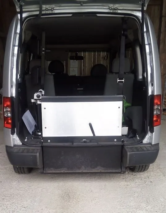 Kofferraum eines Transporters mit Rollstuhlrampe und Notiz auf einem Blatt Papier.