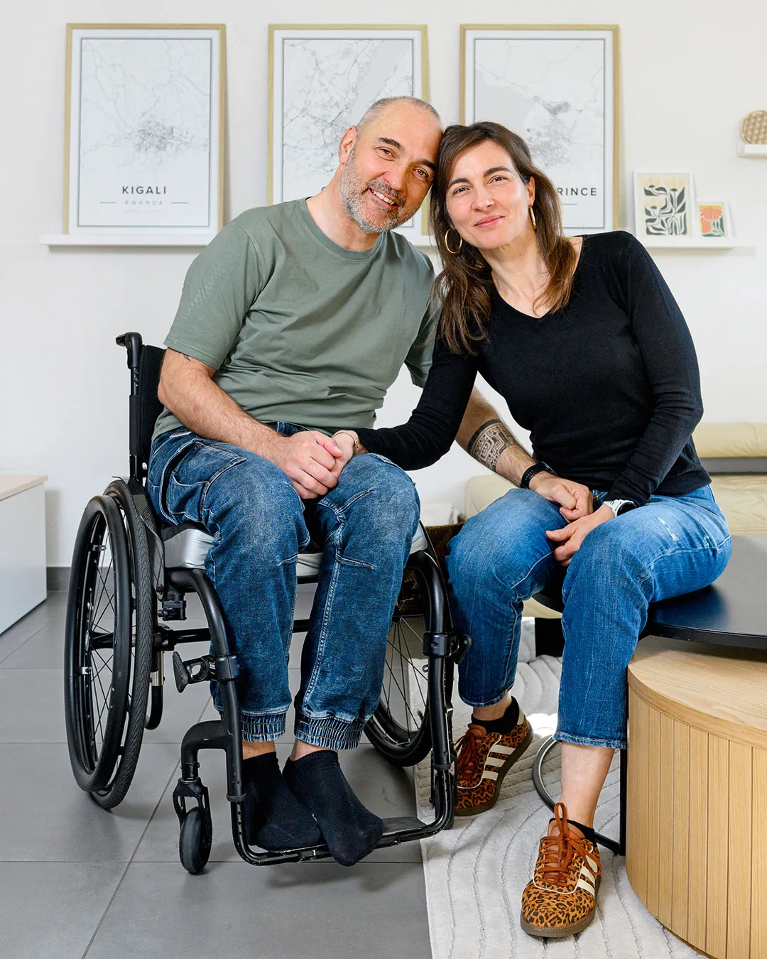 Ein Paar sitzt zuhause eng nebeneinander und hält sich an den Händen, der Mann im Rollstuhl – Liebe, Unterstützung und selbstbestimmtes Leben mit Behinderung im barrierefreien Alltag.