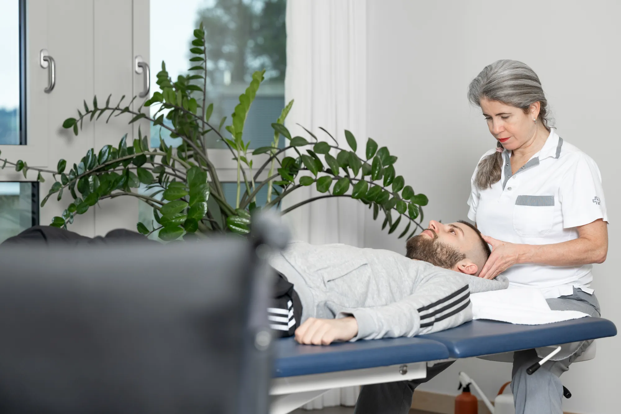 Woman in a medical uniform examining patient on examination table.