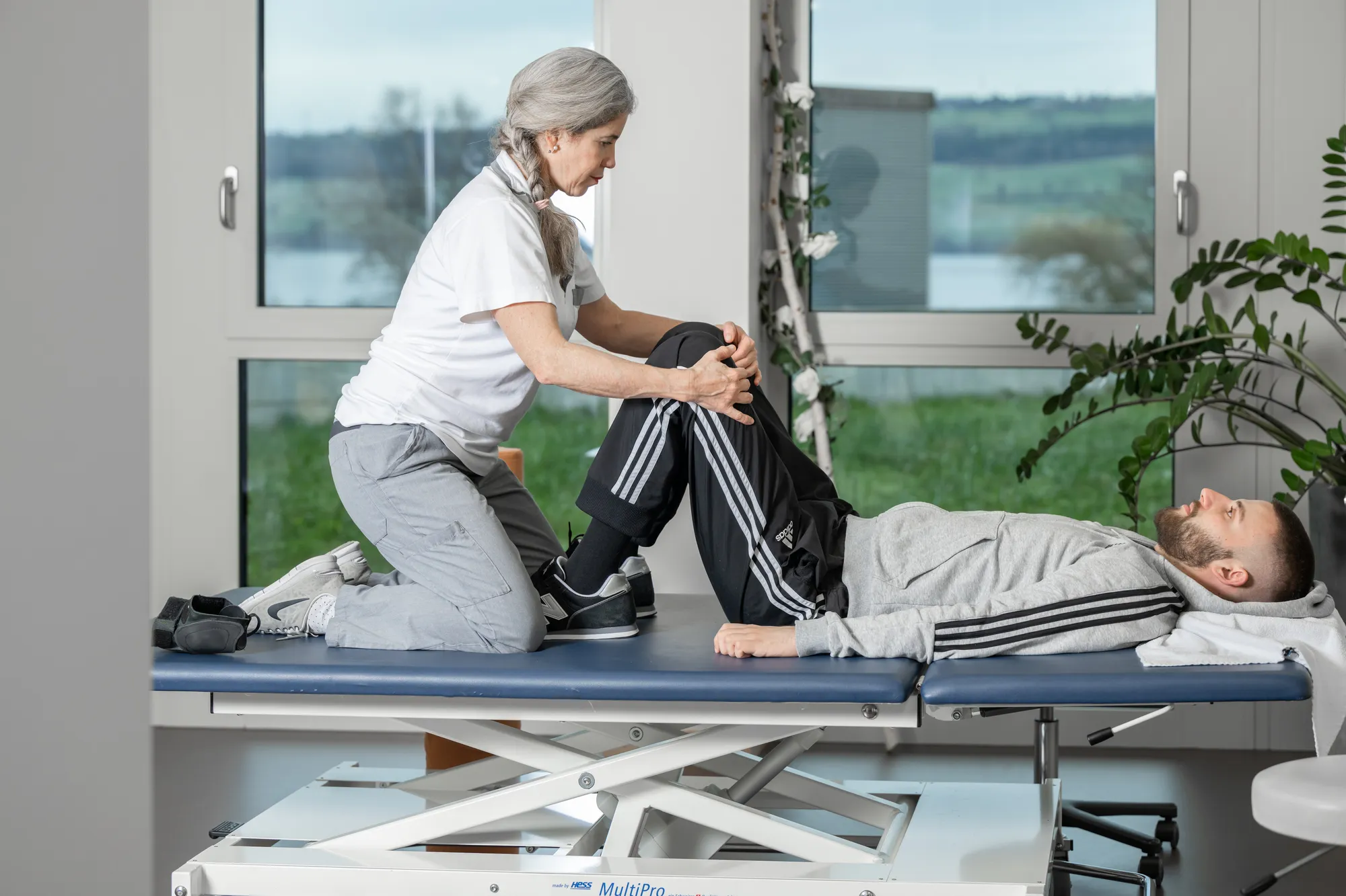 A female massage therapist gives a massage to a young woman on a massage table.