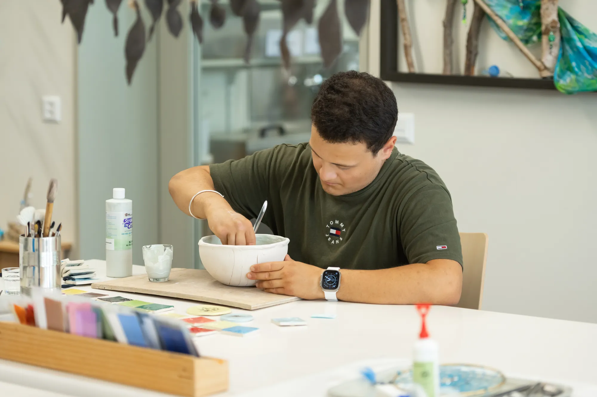 A man sitting at a desk in a creative workspace, intently focused on his work.