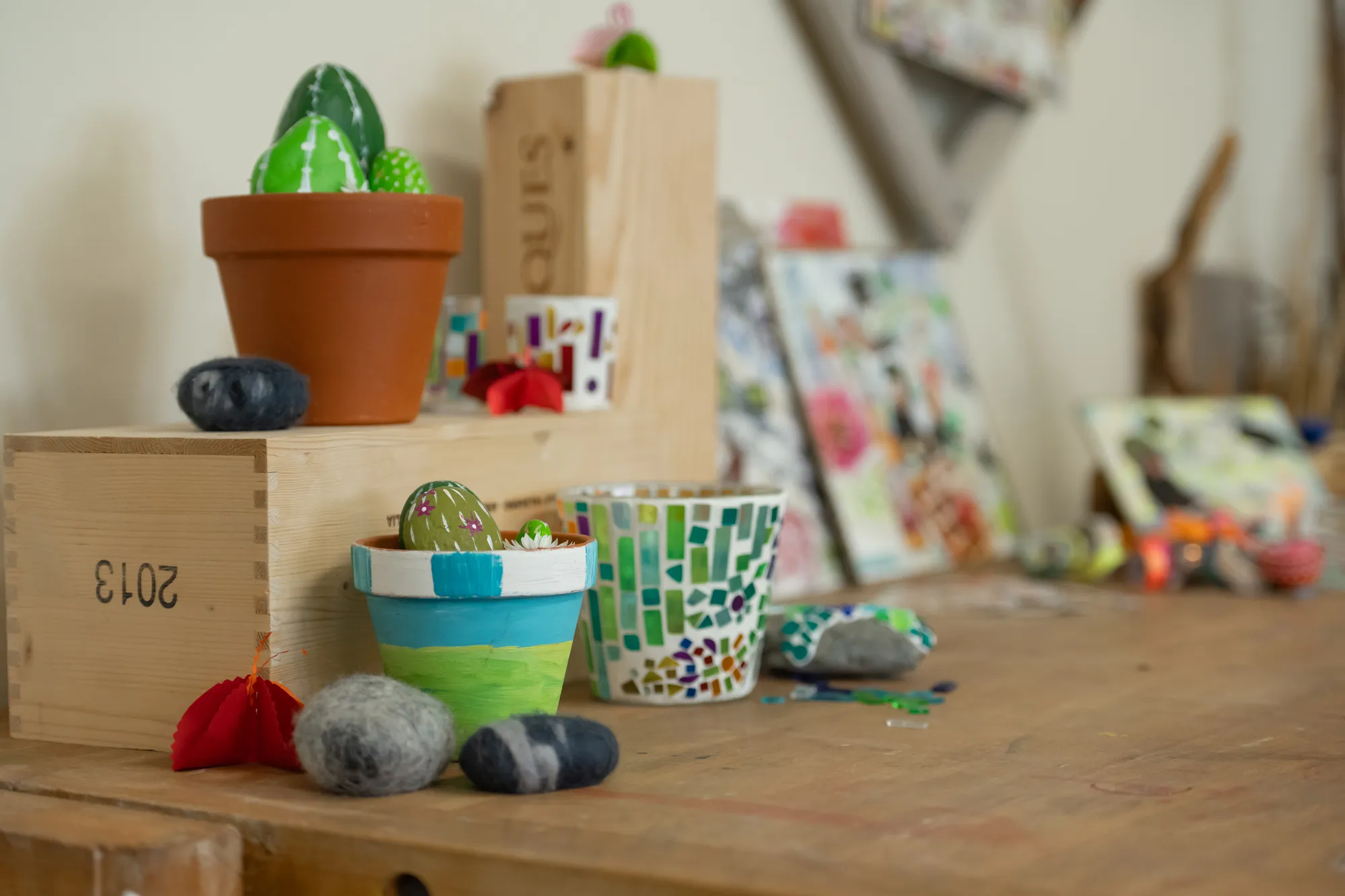 Decorative cactus plant in a terra cotta pot on a rustic wooden table with various small objects and toys.