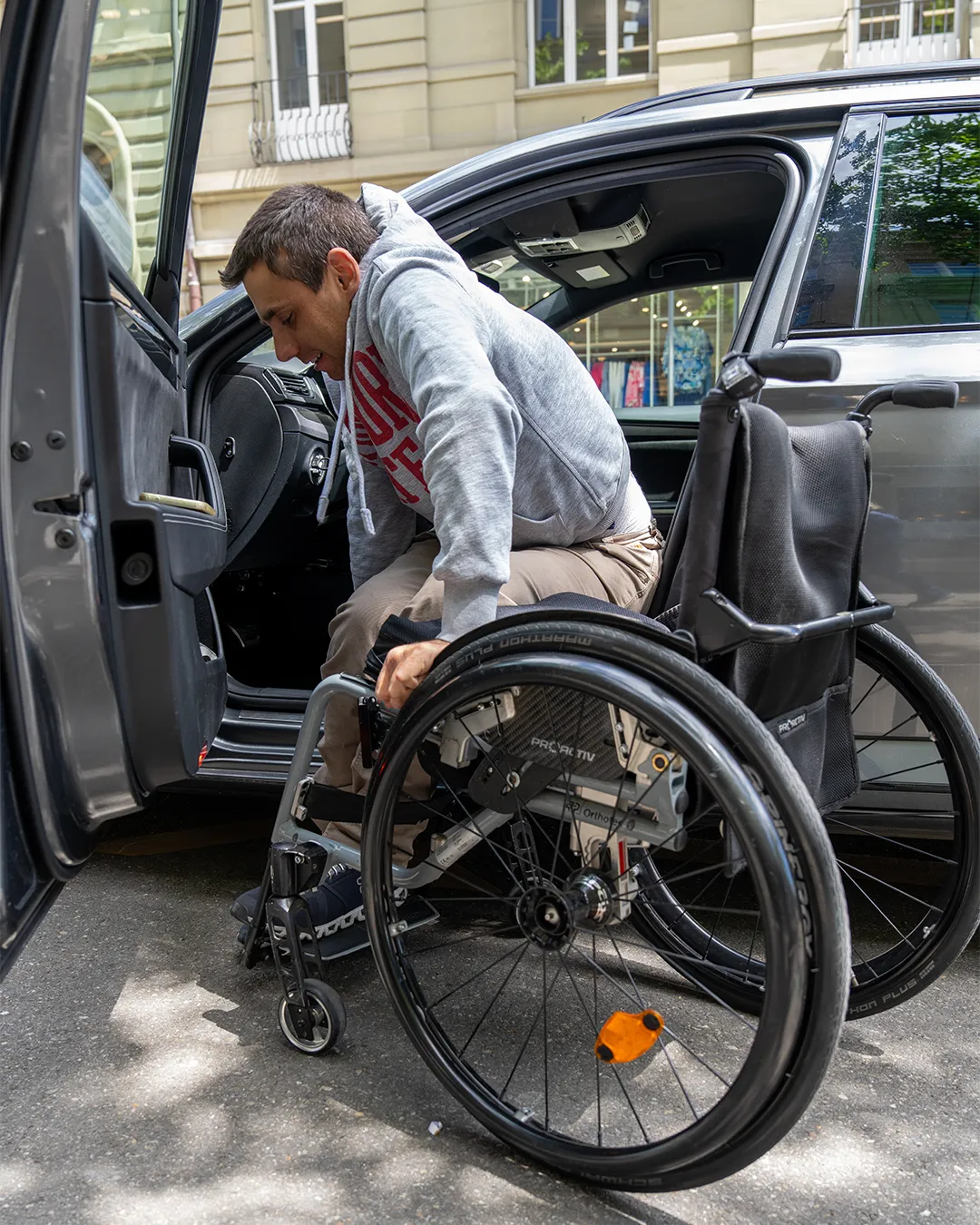 A person in a wheelchair being assisted into a vehicle.