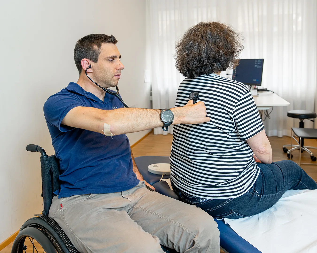 A man in a wheelchair conversing with a woman seated next to him.