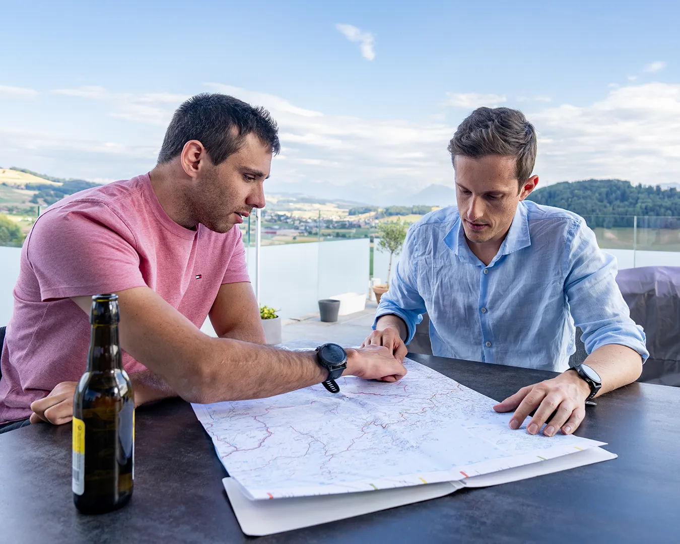 Two men reviewing documents on a dock by the water.