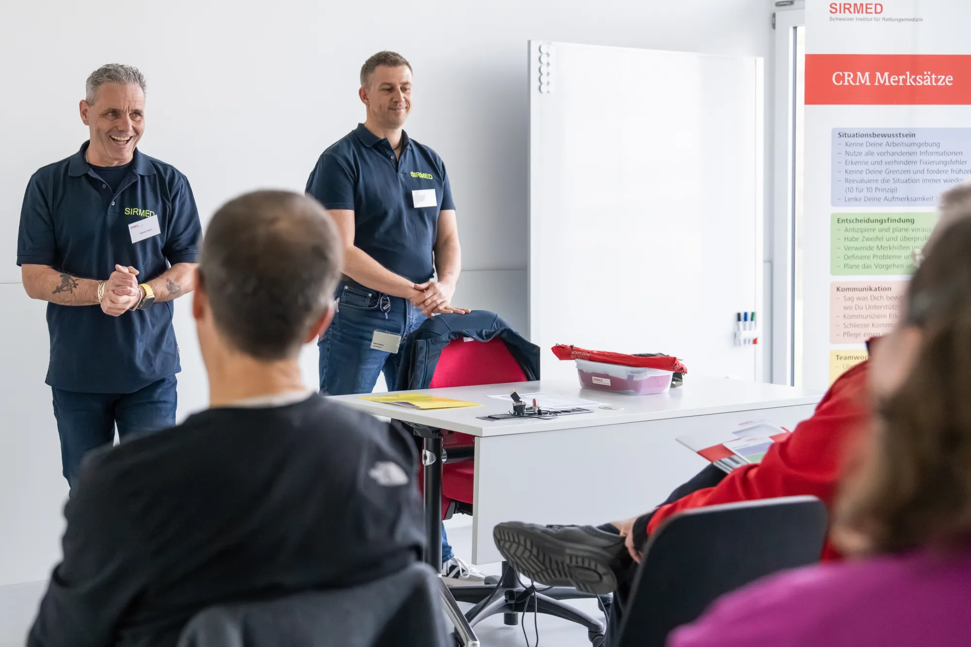Two men presenting to a group in a meeting room.