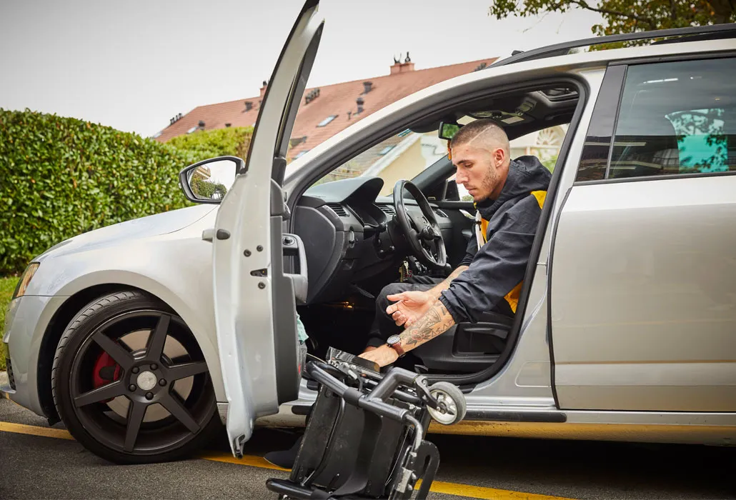 Louka Réal steigt aus seinem Auto aus und klappt den Rollstuhl auf.