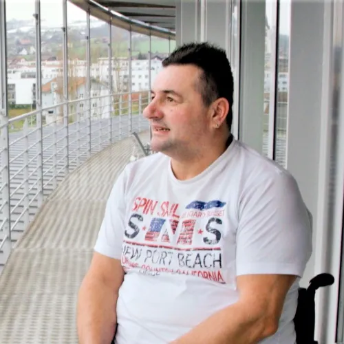 Mann sitzt im Rollstuhl auf dem Balkon