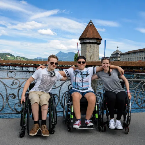 Four people in wheelchairs pose together on a bridge in Lucerne, Switzerland.