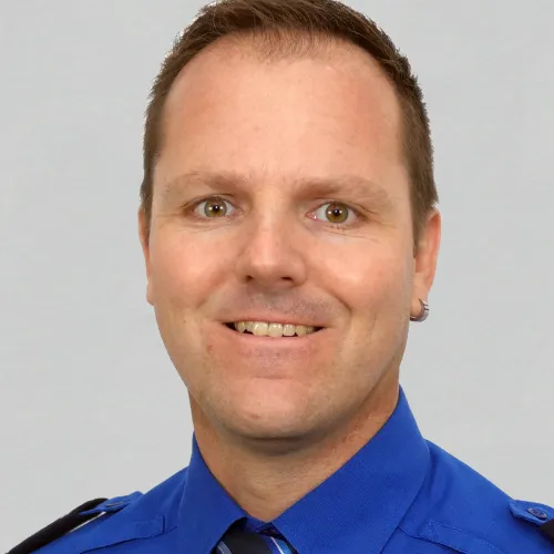 A smiling man in a blue shirt and tie.