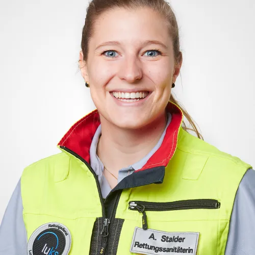 A smiling woman wearing a bright yellow safety vest.