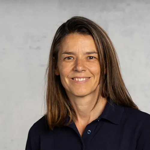 Ein Portraitfoto einer lächelnden Frau mit langen, braunen Haaren.