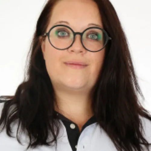Smiling young woman wearing glasses and a white shirt.