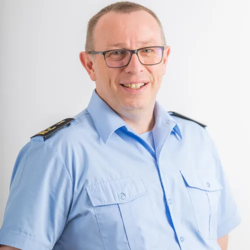 A friendly-looking man in a police uniform, smiling at the camera.