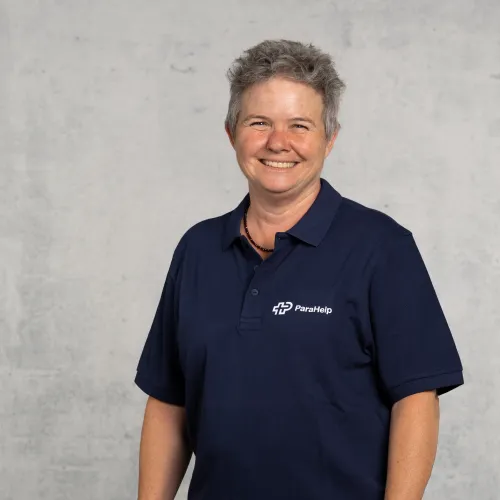 Ein freundlich lächelnde Frau in einem dunkelblauen Poloshirt.
