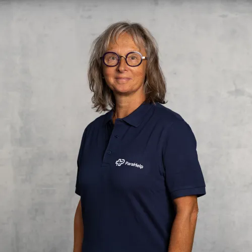 Ein Portrait einer lächelnden Frau mit langen Haaren und einer Brille.