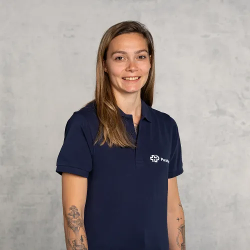 Porträtfoto einer lächelnden Frau mit blonden Haaren, die ein blaues Poloshirt trägt.