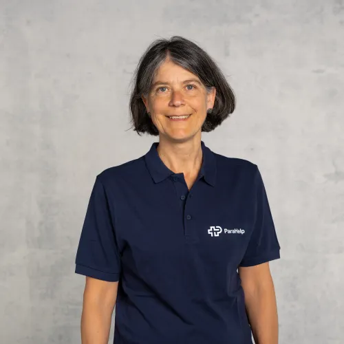 Ritratto di una donna sorridente in una maglietta blu con logo.