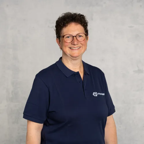 Ein lächelnde Mitarbeiterin in einer blauen Uniform.