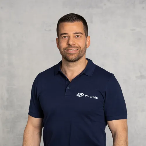 Ein lächelnder Mann mittleren Alters mit braunen Haaren und einem blauen Hemd.