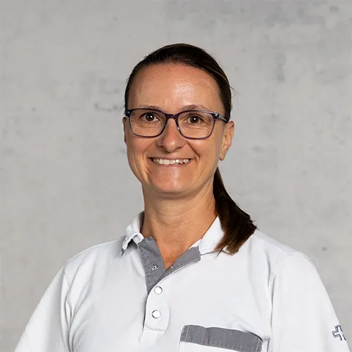 A smiling middle-aged woman wearing glasses and a white shirt.