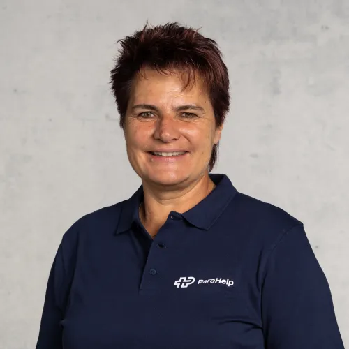 A smiling woman with short brown hair wearing a navy blue shirt.