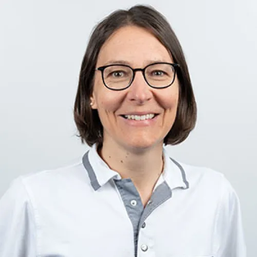 Smiling woman with glasses wearing a white shirt.