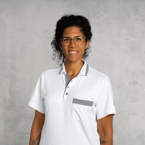 A smiling man in a white collared shirt against a gray background.