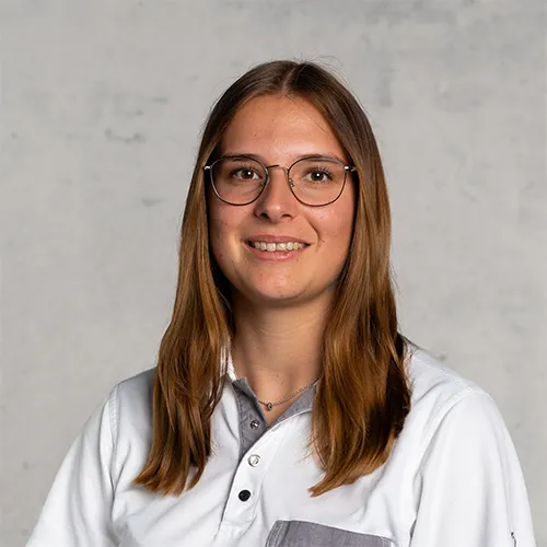 A smiling woman with long brown hair and glasses, wearing a white shirt.